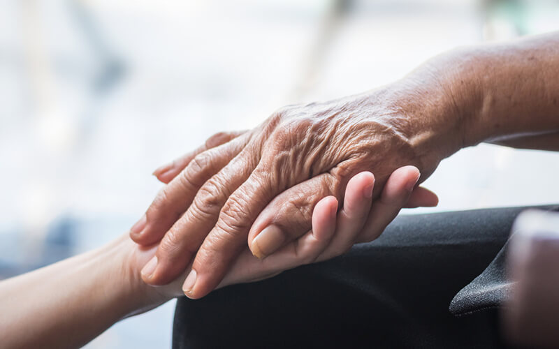 Closeup of family members affected by Parkinson’s disease  holding hands