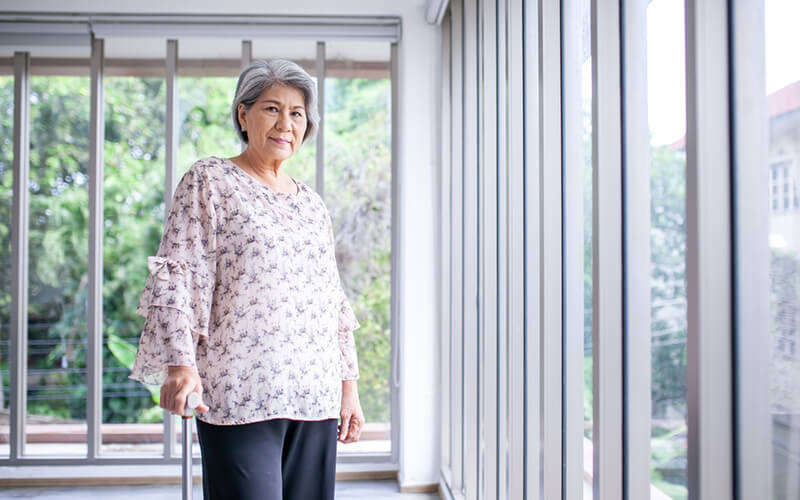 Senior Asian woman with cane looking directly into camera
