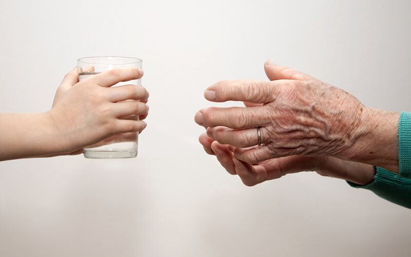 Young hands handing a glass of water to elderly hands