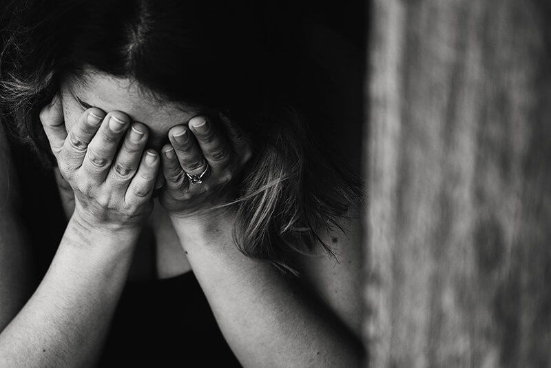 Photo of woman holding her head in her hands as she struggles with anxiety