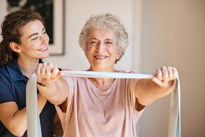 Elderly woman smiling while training with a physical therapist