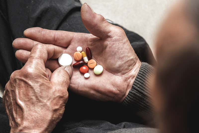 Old person's hand holding a variety of medications