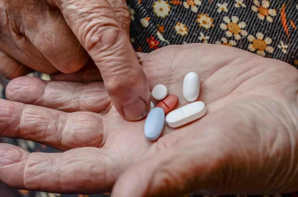 Senior’s hands holding as assortment of pills