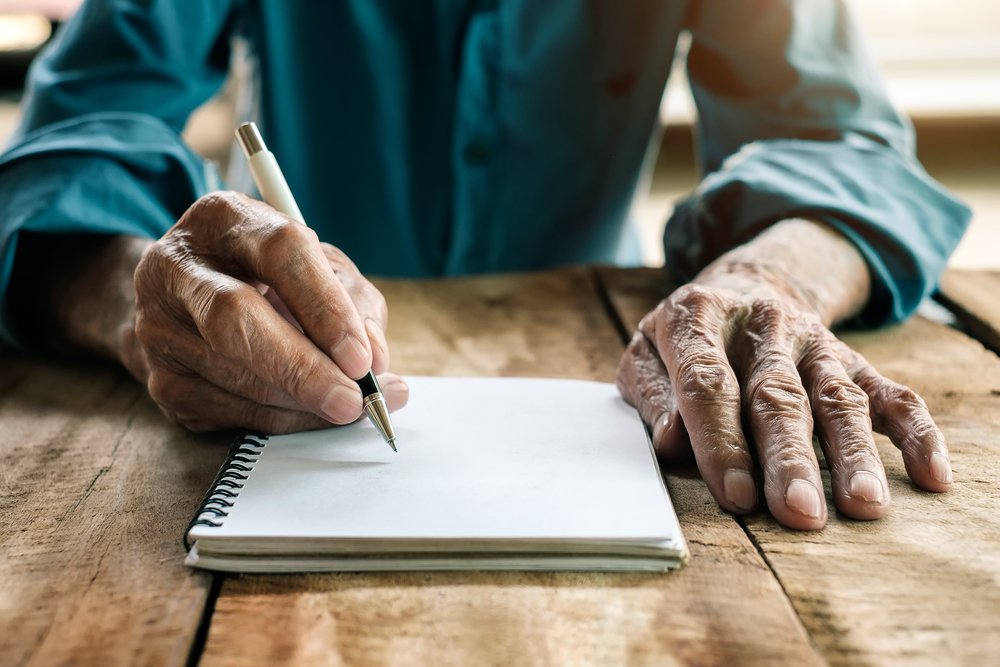 Senior man’s hands writing on paper