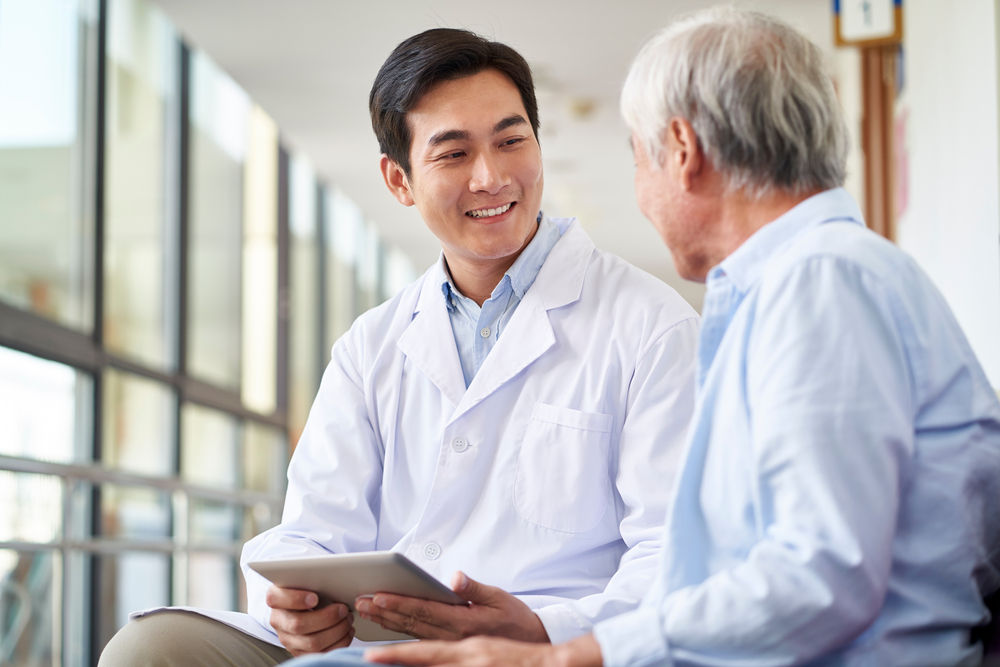 Asian doctor talking to elderly patient